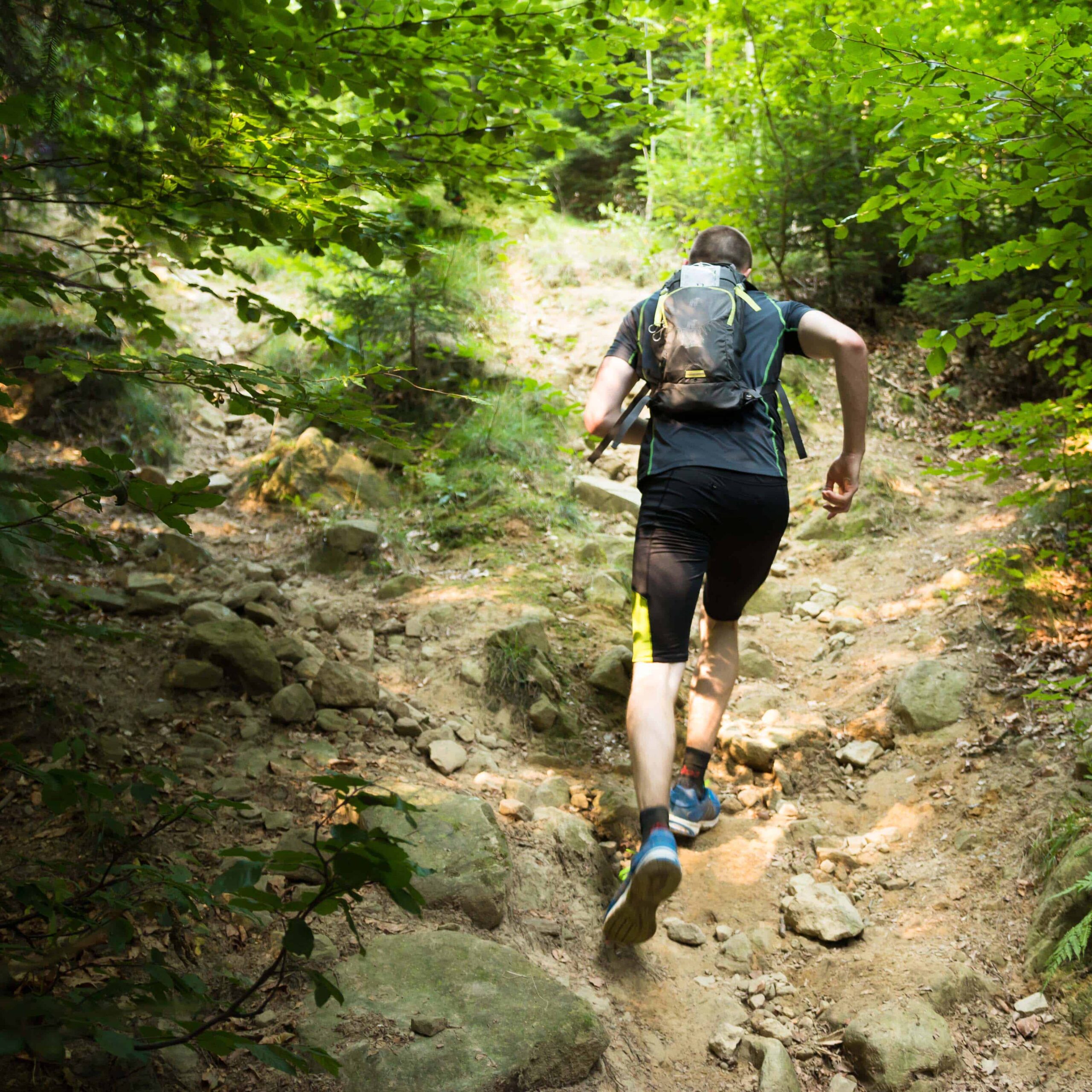 trail runner with backpack running up the steep hill