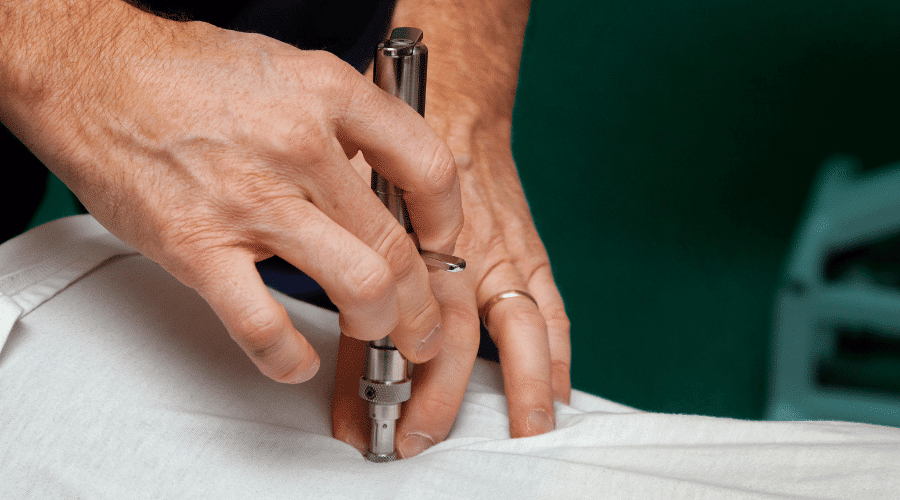Chiropractor performing instrument-assisted adjustment for gentle spinal care